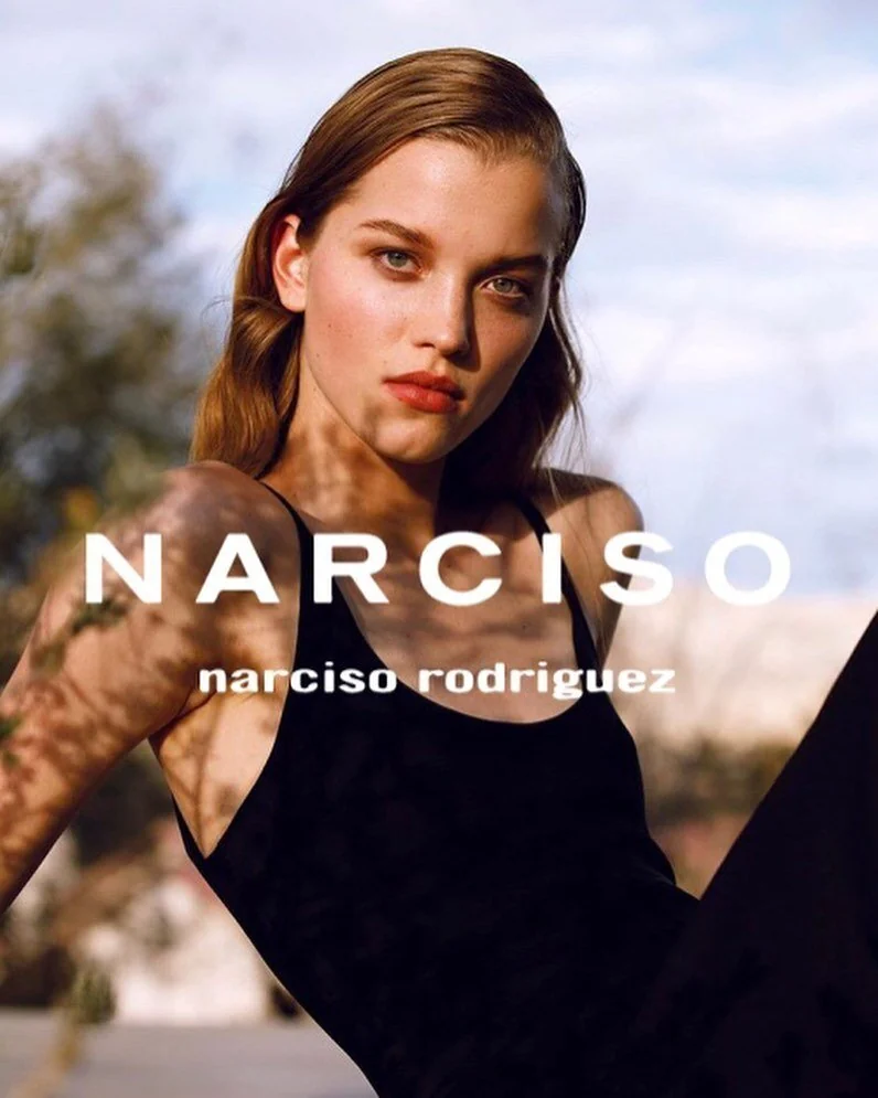 Narciso fragrance campaign portrait of a model in a black top under dappled sunlight.
